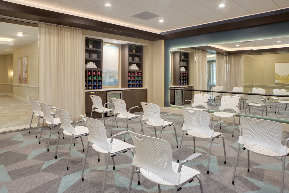 A modern conference room setup with rows of white chairs and a decorative shelf in the background.