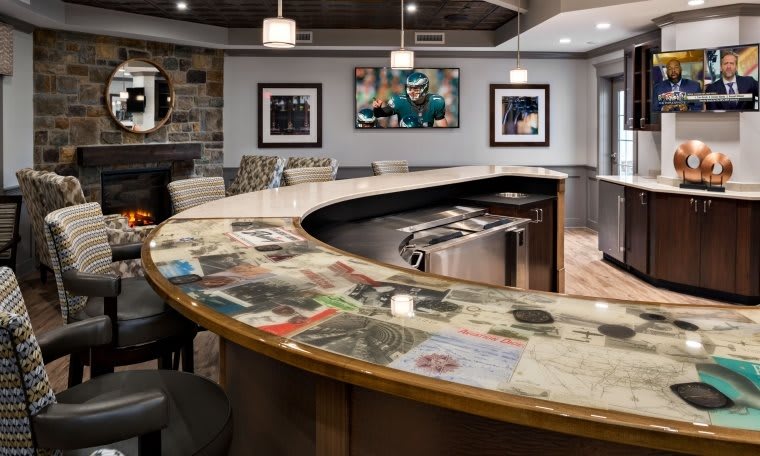 A modern bar interior featuring a curved countertop with embedded images, stylish seating, and contemporary artwork on the walls.