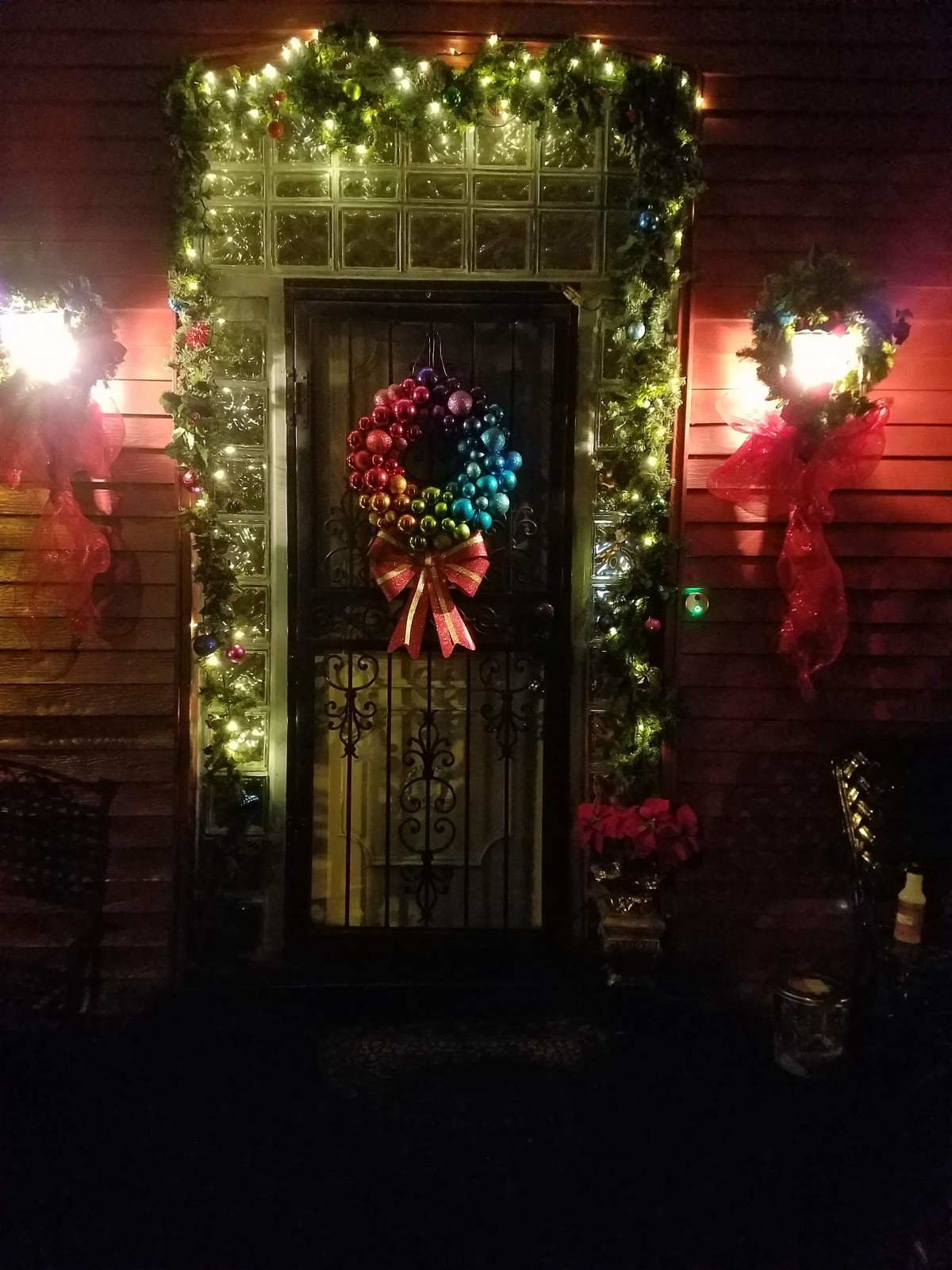 A festive front door decorated with a colorful Christmas wreath and glowing lights.