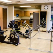 A rehabilitation gym equipped with a stationary bike and parallel bars.