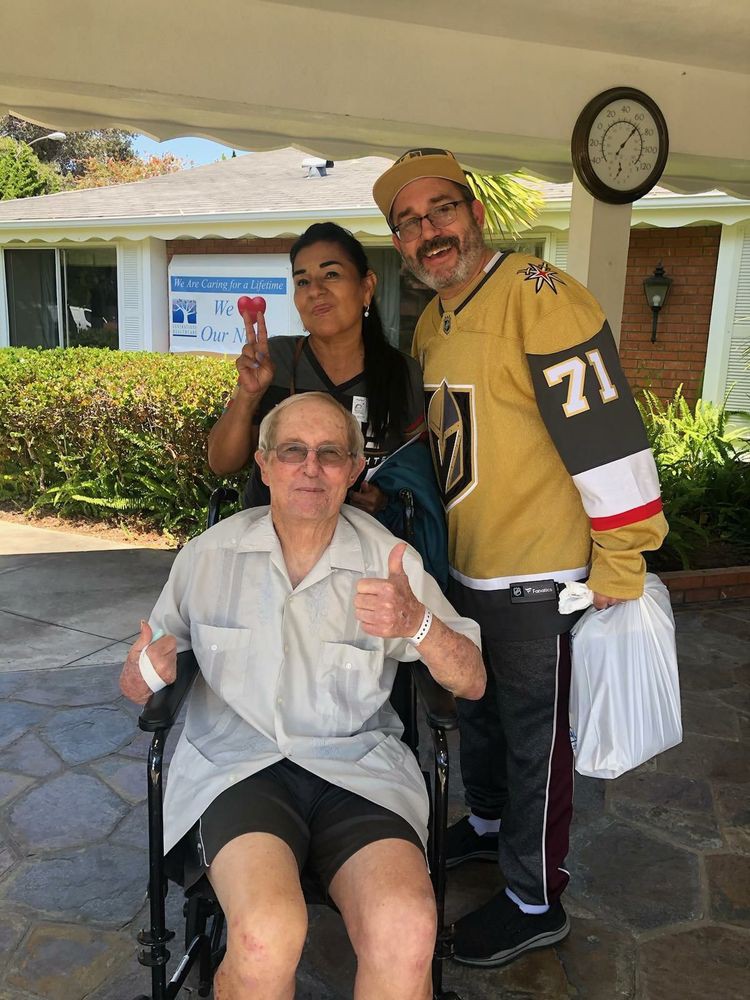 A smiling group poses outdoors with one person in a wheelchair.