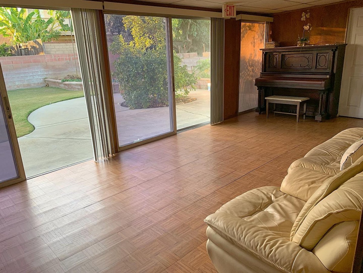 A cozy living room with a piano, sliding glass doors, and a comfortable sofa.
