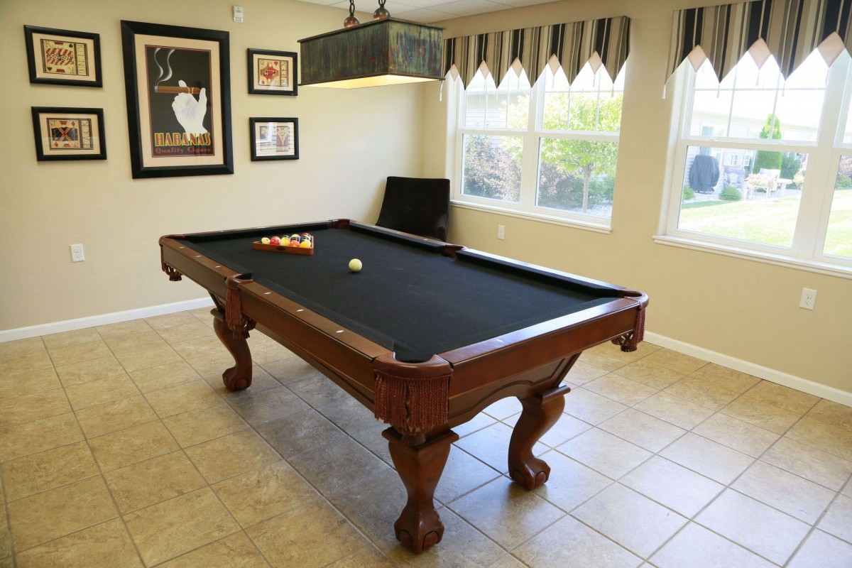 A billiards table with black felt in a well-lit game room.