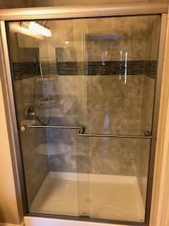 A modern shower with a glass door and tiled interior.