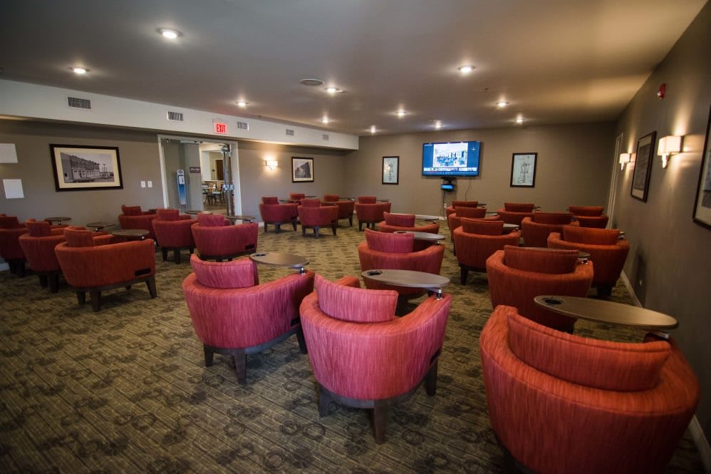 A spacious lounge with red chairs and a television.