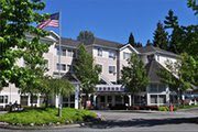 A hotel building with trees in front and an American flag waving on a sunny day.