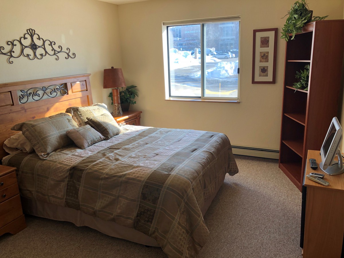 A cozy bedroom with a neatly made bed, window, and decorative elements.