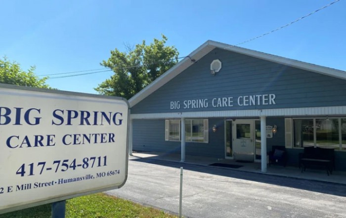 A sunny day view of the Big Spring Care Center with a sign in the foreground.