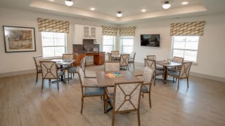 A well-lit dining room with neatly arranged tables and chairs.