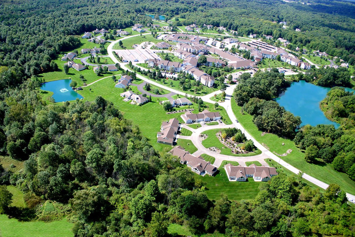 Aerial view of a residential community surrounded by lush greenery and small lakes.