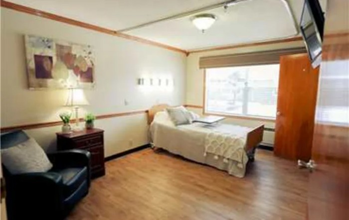 A cozy bedroom with a single bed, large window, and comfortable furnishings.