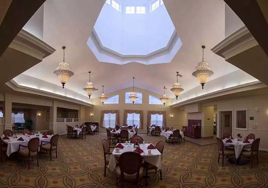 A spacious dining room with elegant chandeliers and a large skylight.