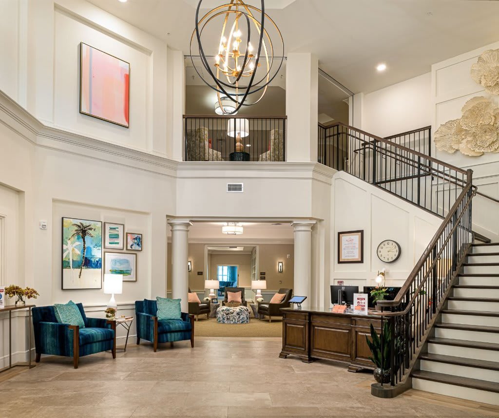 A spacious and elegantly designed lobby featuring a grand staircase, modern furniture, and a stylish chandelier.