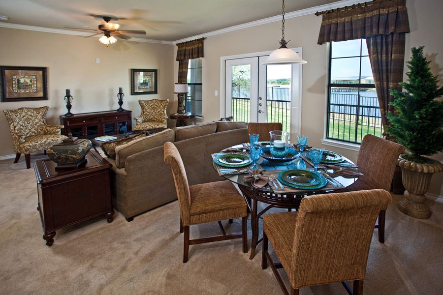 A cozy living and dining area with a sofa, dining table set, and large windows allowing natural light to illuminate the space.