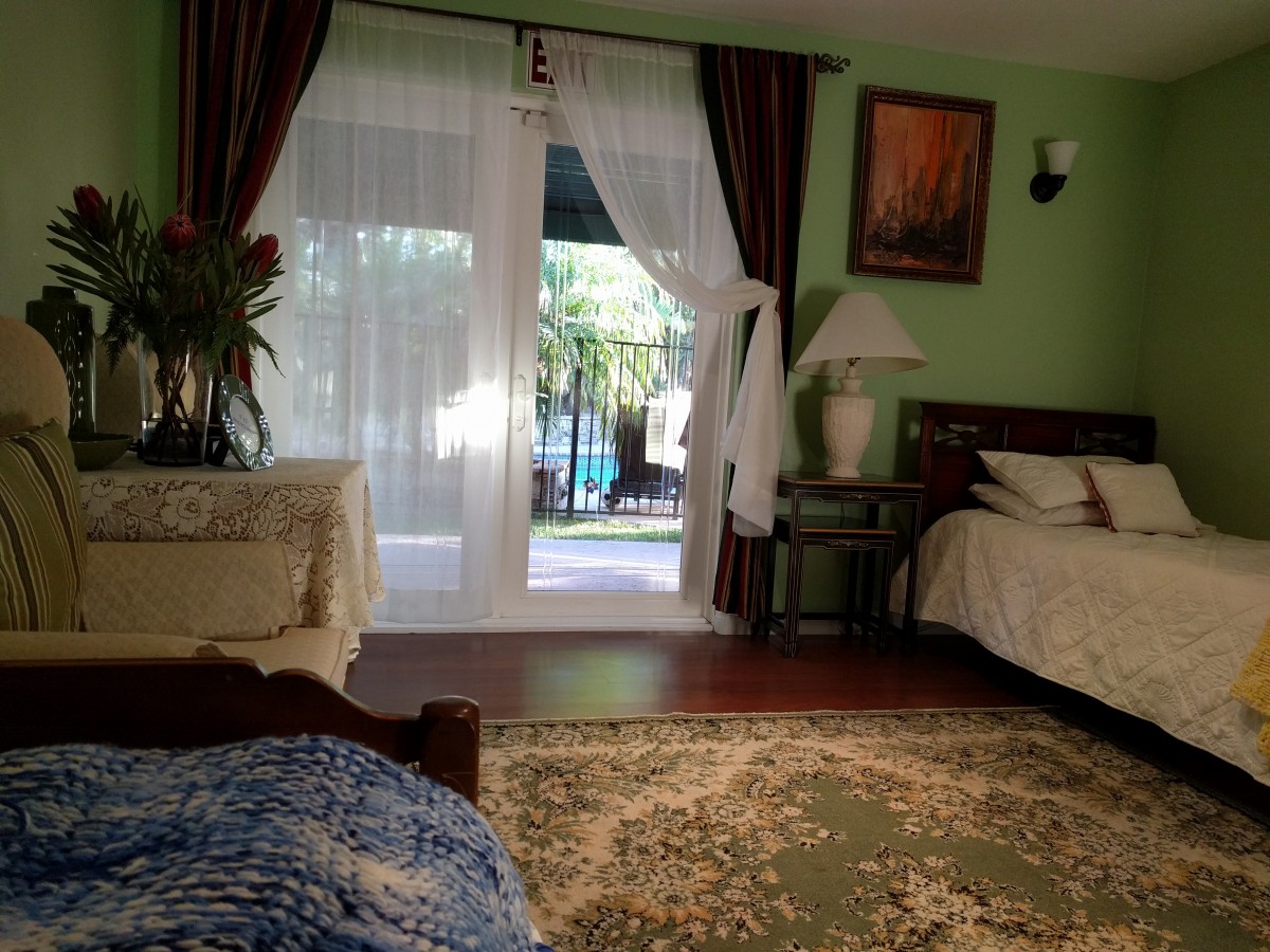A cozy bedroom with a large window, elegant curtains, and classic furniture.