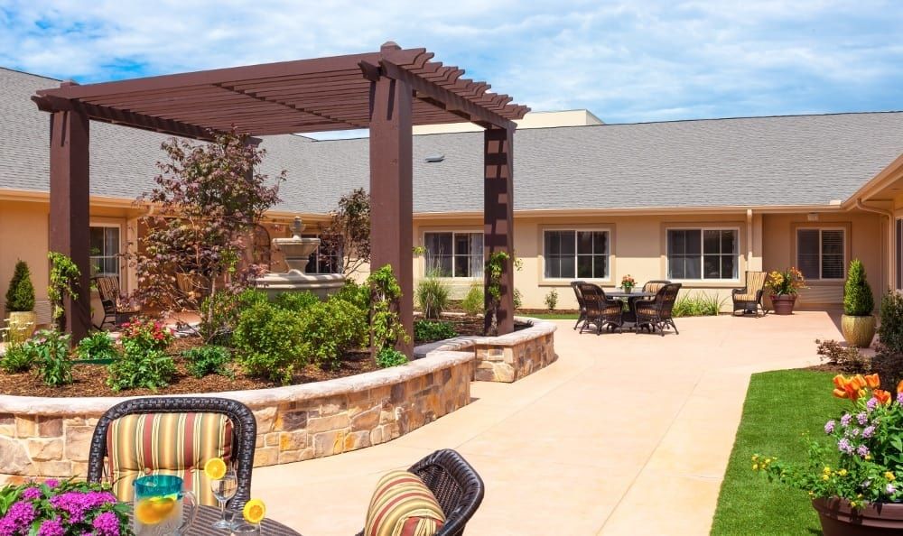 A sunny courtyard with a pergola, garden, and outdoor seating.