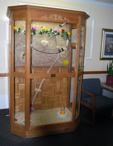 A decorative wooden birdcage with flowers and perches.