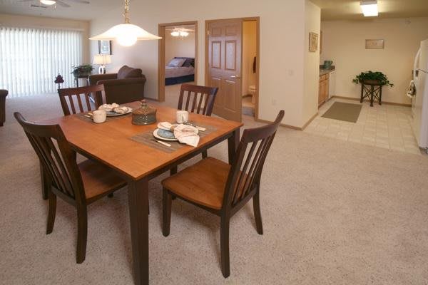 A cozy dining area with a wooden table and chairs, set in a carpeted room.