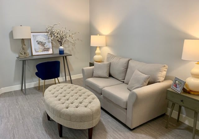 Cozy living room with a beige sofa, elegant ottoman, and soft lighting.