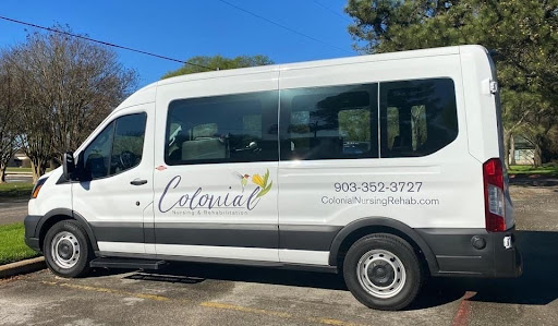 A white van with the name 'Colonial' displayed on its side, parked in a sunny location.