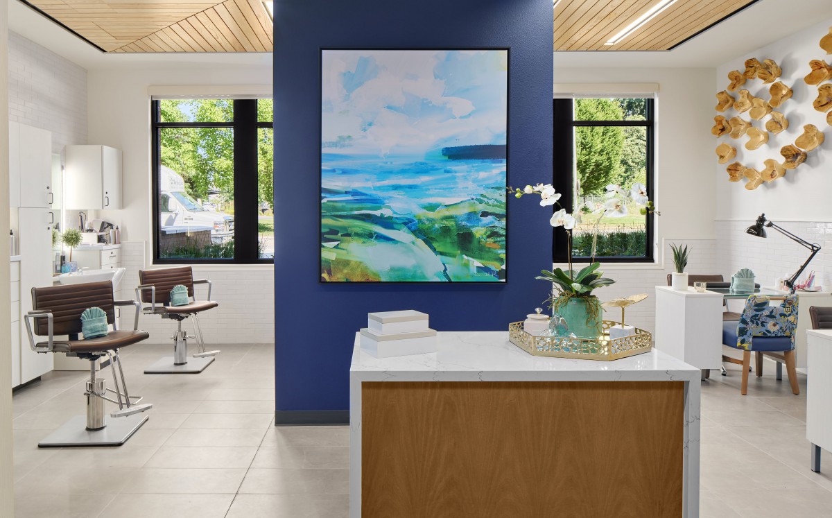 A modern reception area featuring a large abstract painting on a blue accent wall, with natural light streaming in through the large windows.