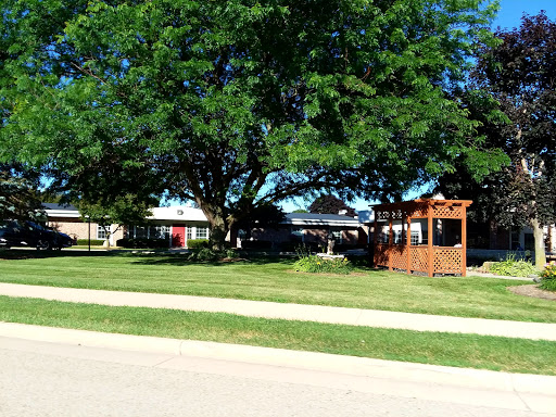 A peaceful suburban scene featuring a house surrounded by lush greenery and a charming gazebo.