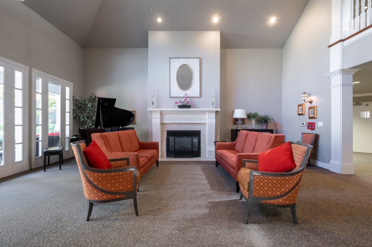 A modern living room featuring a grand piano and symmetrical seating arrangement around a fireplace.