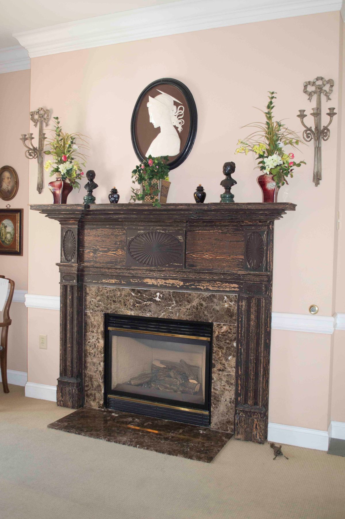 A vintage-style fireplace with a decorative mantelpiece adorned with flowers and silhouette art.