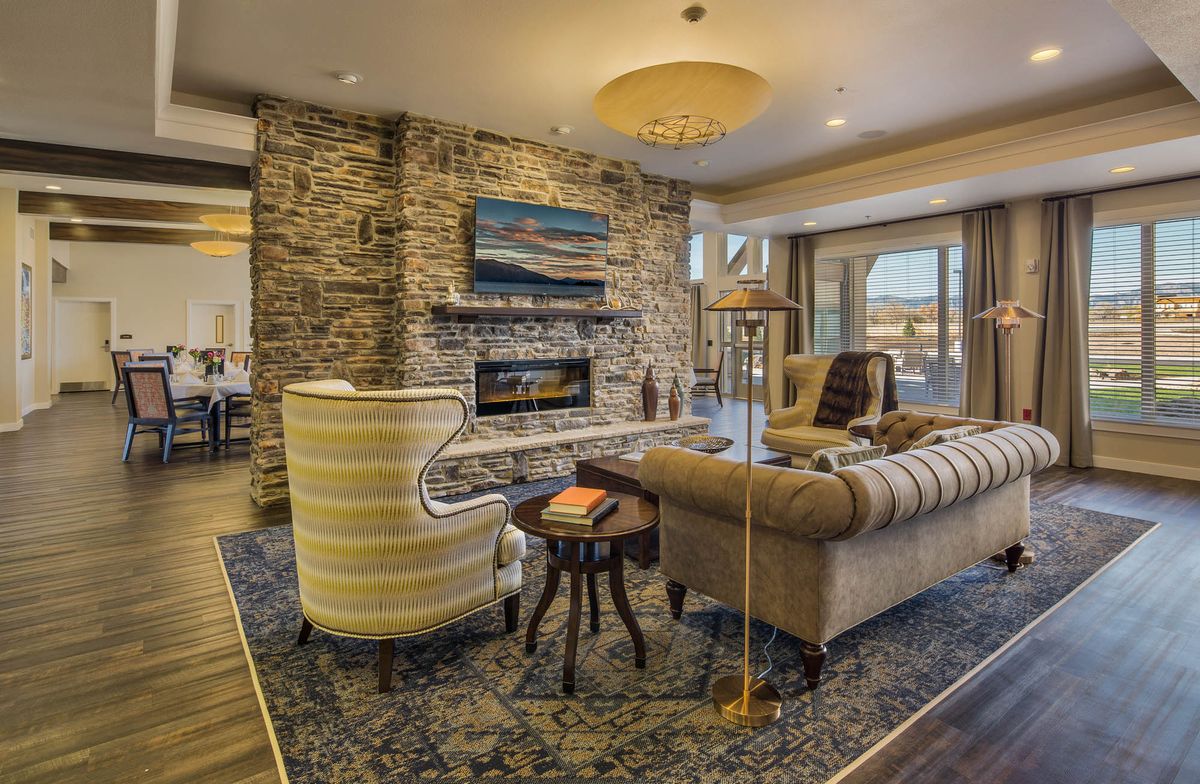 A cozy and elegant living room with a stone fireplace, plush seating, and warm lighting.