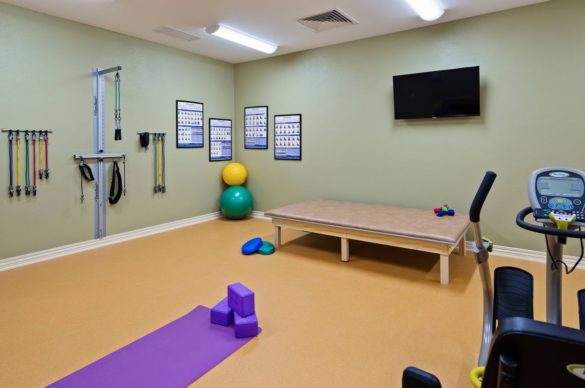 A well-equipped exercise room featuring a yoga mat, exercise balls, and fitness posters.