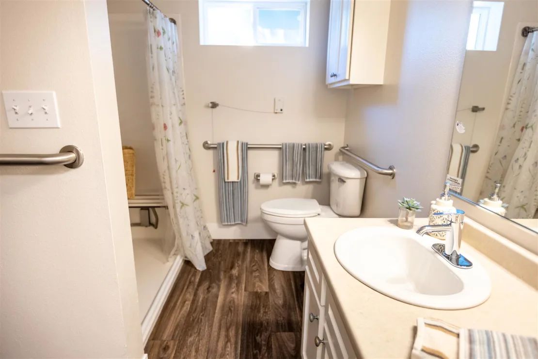 A modern bathroom with a shower, toilet, and sink, featuring stylish flooring and neatly arranged towels.