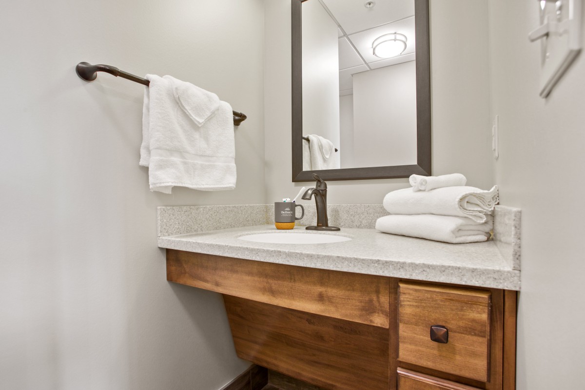 A clean and modern bathroom featuring a wooden countertop, towels, and a large mirror.