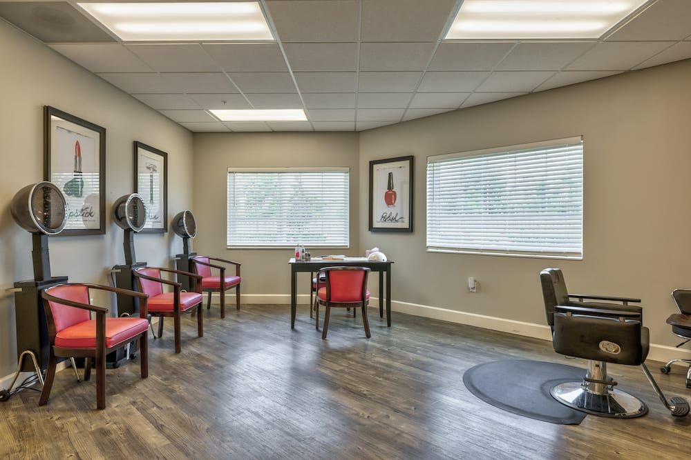 An empty salon with a waiting area featuring chairs, a desk, and artwork on the walls.