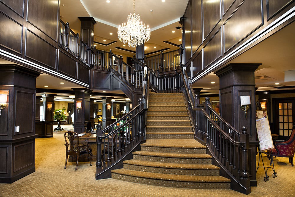 A luxurious hotel lobby featuring a grand staircase and chandelier.