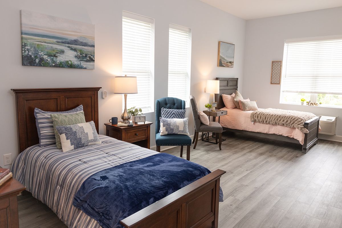 A modern bedroom featuring two twin beds, stylish decor, and wooden flooring.