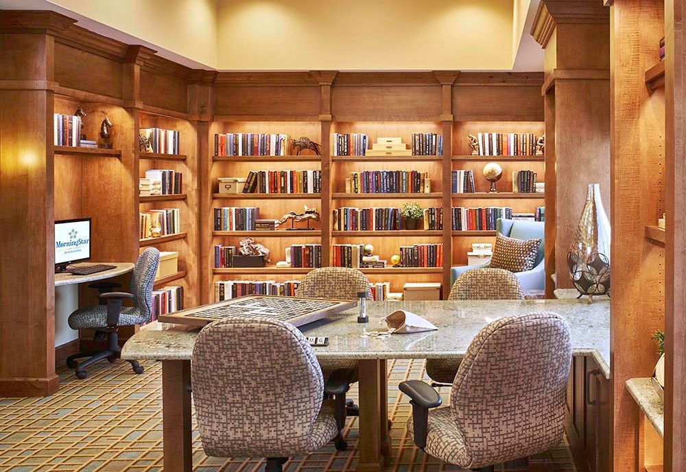 A cozy library with wooden shelves filled with books, and comfortable seating for reading.