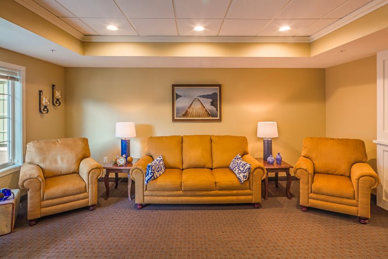 A cozy living room with mustard sofas and armchairs, complemented by lamps and wall art.