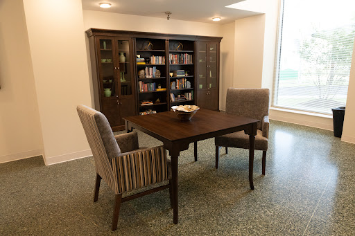 A cozy dining area featuring a wooden table and striped chairs, accompanied by a bookshelf filled with books.