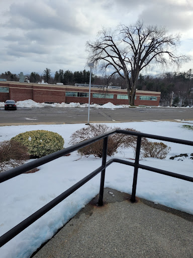 A winter scene showing a snowy landscape with a tree and a building in the background.