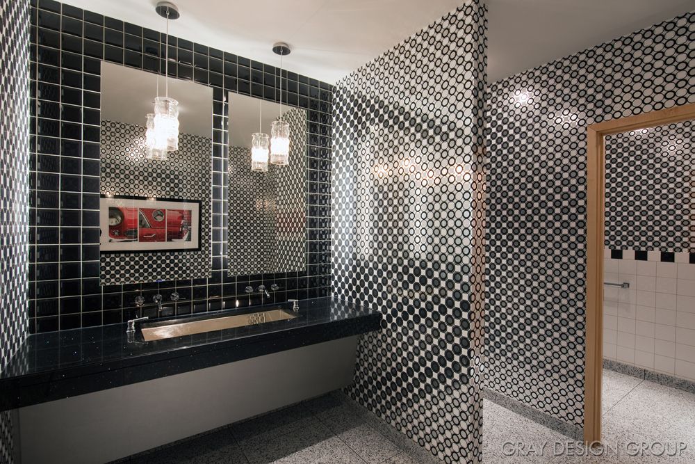 A modern bathroom with black and white geometric tiles, a large mirror, and stylish lighting.