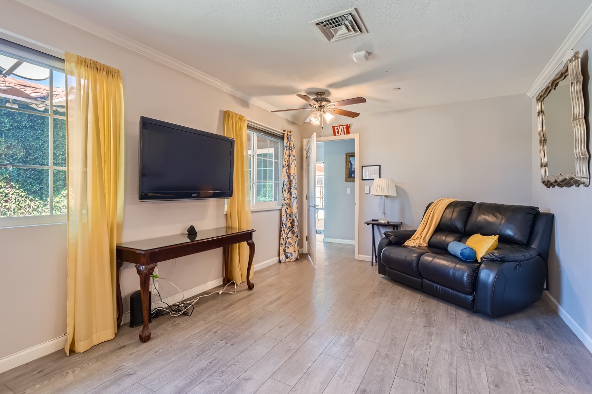 A cozy living room with a television, sofa, and yellow curtains.