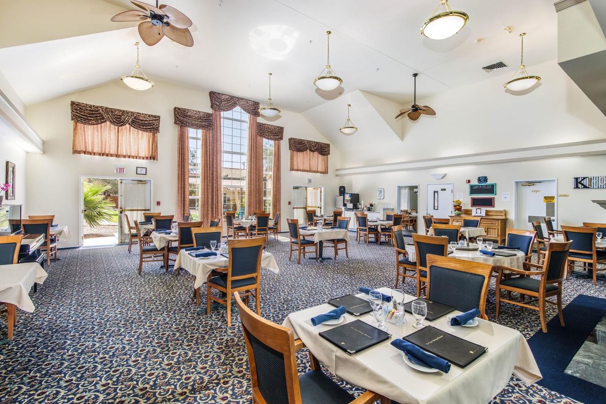 A spacious dining room with elegantly set tables and ceiling fans.