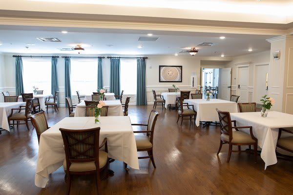 A spacious dining room with neatly arranged tables and chairs, featuring elegant decor and bright lighting.