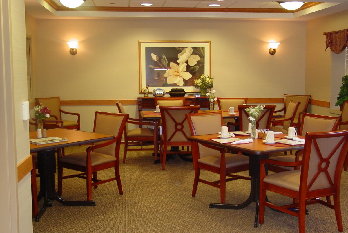A cozy dining area with neatly set tables and chairs, complemented by elegant wall art.