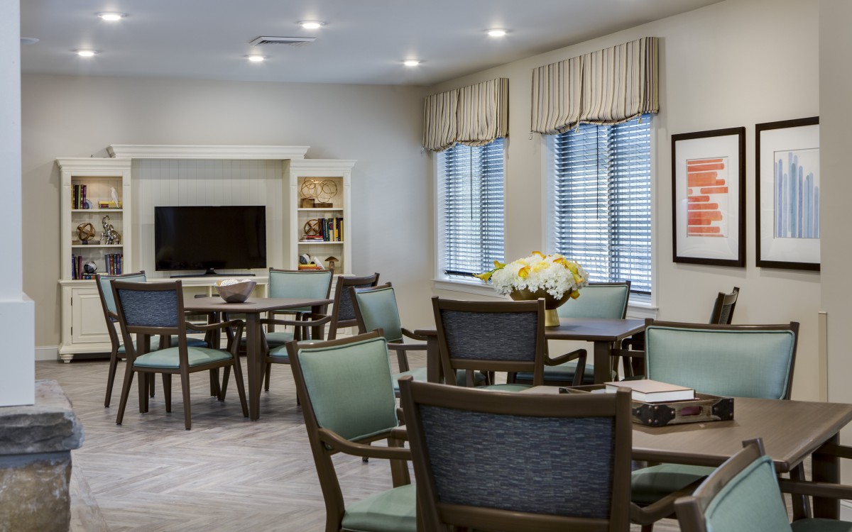 A cozy living area with multiple tables and chairs, a TV, and decorative elements.