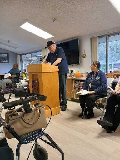A speaker addresses an audience during a meeting at a community center.