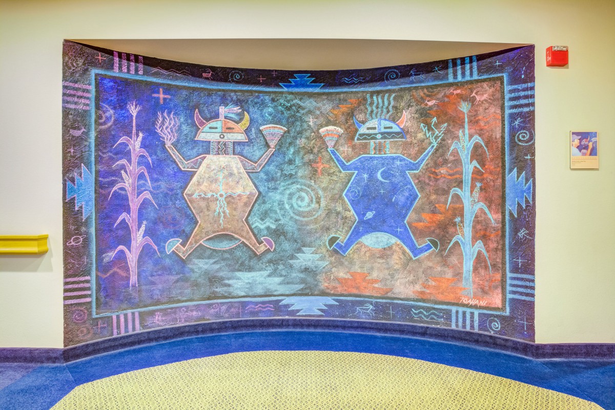 A colorful and abstract mural featuring geometric figures and cultural symbols.