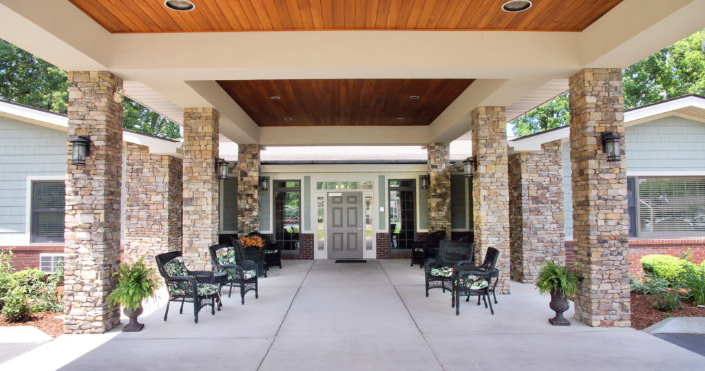 A building entrance with stone pillars and outdoor seating.