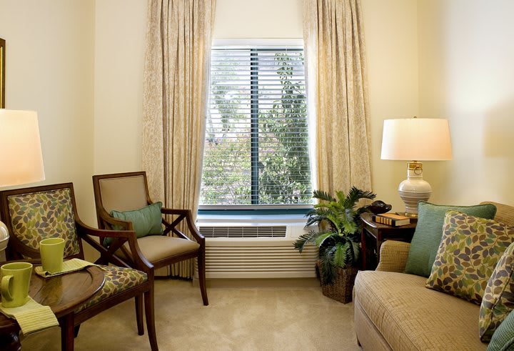 A cozy living room with elegant furniture, a potted plant, and a window with curtains.