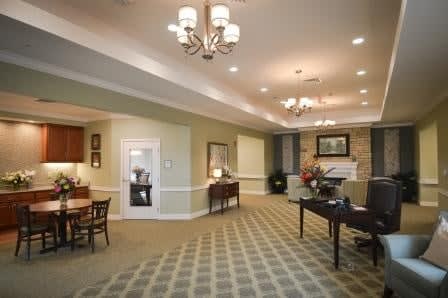 A warmly lit lobby with elegant chandeliers, a decorative carpet, and comfortable seating.